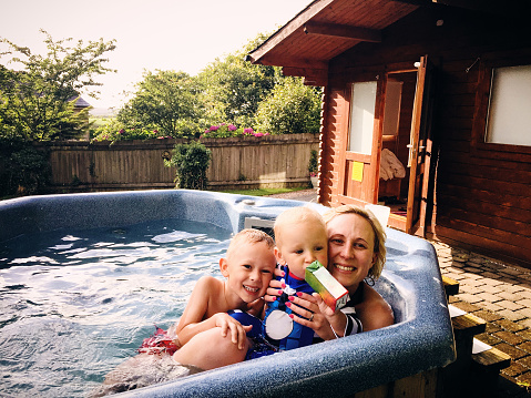 Mom with young kids in outside hot tub