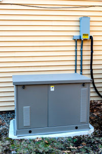 Residential generator on concrete pad, next to a house wall