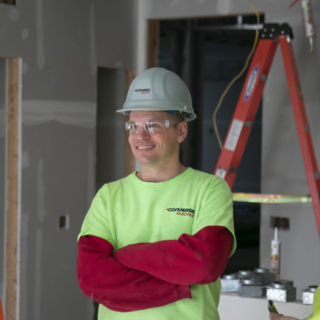 Converse Electric technician smiling on the job site with arms folded