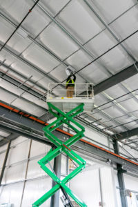 Converse Electric technician on a lift working on ceiling electric box