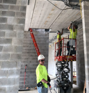 Converse Electric team on a lift running conduit on ceiling