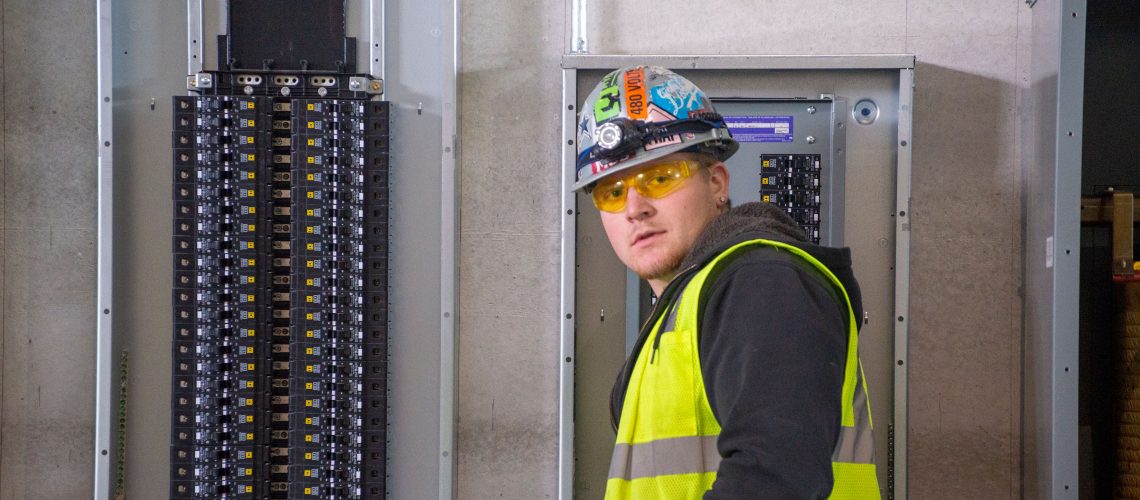 Converse Electric technician standing in front of electric panel