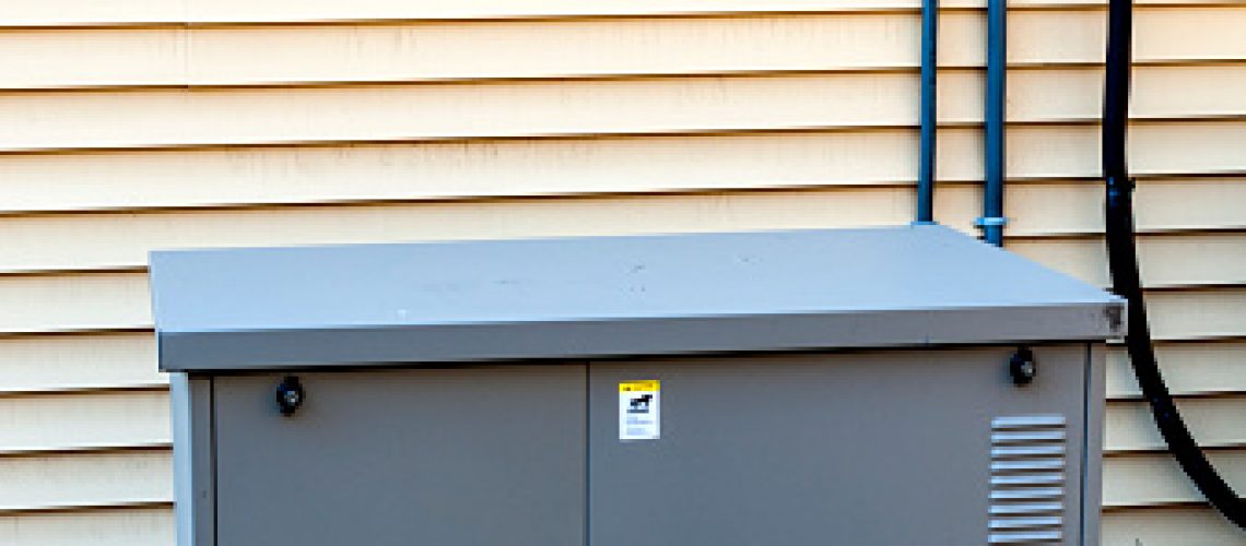 Residential generator on concrete pad, next to a house wall