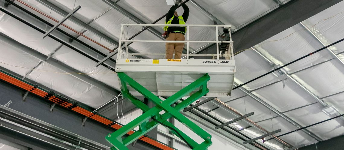 Converse Electric technician on a lift working on ceiling electric box